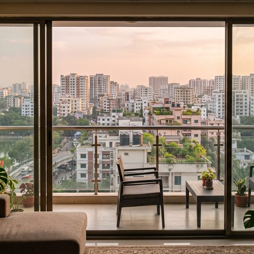 Living room with a balcony overlooking the Dhaka skyline at sunset