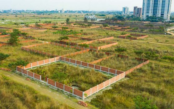 Aerial view of brick-walled residential plots on open land near Dhaka